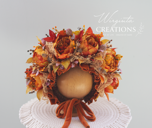 Wirginta Creations Burnt Orange artificial Flower bonnet placed on a wooden round stand. Bonnet decorated with velvet ties and matching lace. Boho style