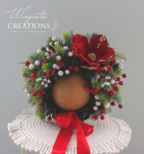 Load image into Gallery viewer, Christmas-themed baby headpiece with artificial red flower, berries, pinecones, and greenery, arranged around a rounded base with red ribbon bow. Designed for short-term wear and seasonal photography for babies aged 6–24 months.