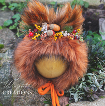 Load image into Gallery viewer, Decorated fox bonnet for 9-24 months old. Faux fur, burnt orange headpiece placed on a wooden ball stand. Greenery background. Photography prop. creator -  Wirginta Creations