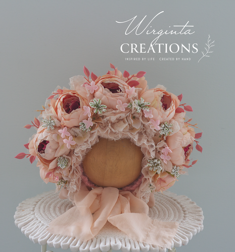 Light peach peonies flower bonnet for 12-24 months old placed on a wooden oval stand. artificial flower headpiece. Brand: Wirginta Creations