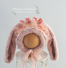 Load image into Gallery viewer, Tattered style bunny bonnet, handmade, pastel pink colour, faux fur ears, knitted base. Bonnet placed on a wooden ball stand. Wirginta Creations the creator. Size: 6-24 months old, photography prop. Easter