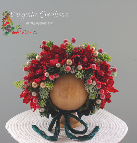 Christmas themed flower bonnet with green and red accents. Bonnet is placed on wooden oval stand. Photography prop. Creator-Wirginta Creations